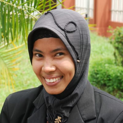 En muslimsk kvinna i Malaysia tittar leende in i kameran.