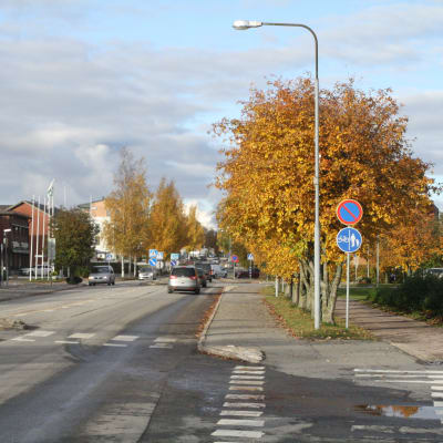 Bilar som kör på huvudgatan i Närpes. Träden vid sidan om vägen är i höstskrud.