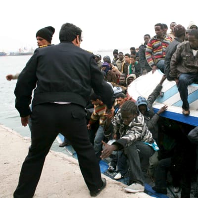 Libyan poliisi auttaa siirtolaisia ulos täyteen ihmisiä ahdetusta veneestä Tripolissa. 