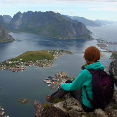 Person sitter och ser ut över en fjord