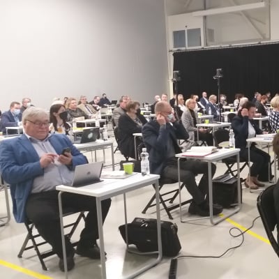 Väkeä istumassa salissa.