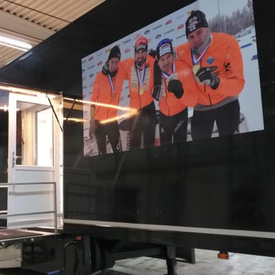Tumma, noin 20 metriä pitkä vaunu, jonka seinällä hiihtäjien kuvia.