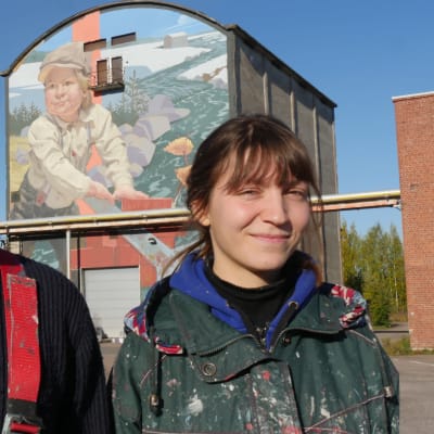 Taiteilijat Taneli Stenberg ja Anetta Lukjanova muraalin edustalla Kuusankoskella Kymin Ruukin alueellae