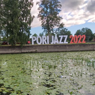 Puistomaiseen luotoon vievän, joen ylittävän ponttoonisillan pielessä lukee isoilla mainoskirjaimilla Pori Jazz 2022.