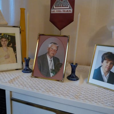 På ett bord hemma hos Gurli Nurmi finns fotografier på hennes avlidna man och döttrarna som också gått bort