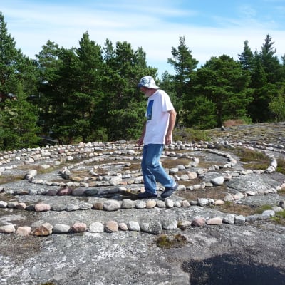 Janne Gröning går i en spiral av sten. Spiralen finns på ett berg i Keistiö, Åboland