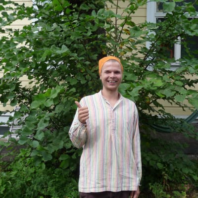 Andreas Wiberg i sin trägård i Åbo. Visar tummen upp och ler.