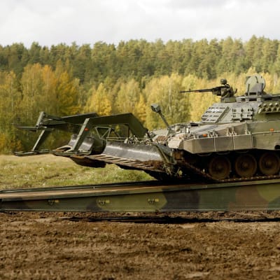 Bild på en Leopard 2-minröjningsvagn, i bakgrunden grön skog.