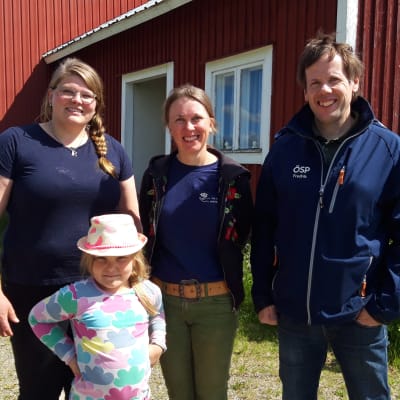 tre vuxna och en flicka på en gård