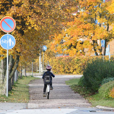 Ett barn kör med cykel längs med en trottoar i Närpes.