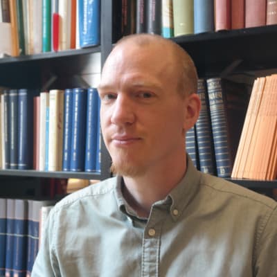 Universitetslärare Patrik Hagman framför en bokhylla