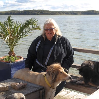 Britt-Marie Juup med två hundar på en brygga med havet i bakgrunden