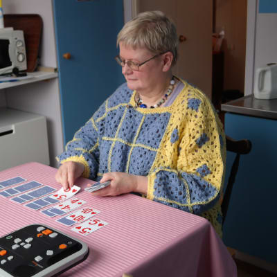Gunilla Löfman sitter vid sitt köksbord och lägger patiense