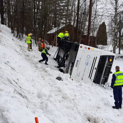 En buss har kört i diket och ligger på sidan, räddningsmanskap jobbar