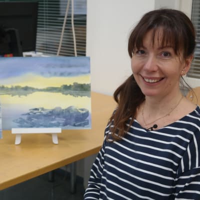 Konstnären Victoria Yaroshik framför två havsakvareller