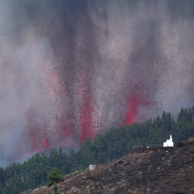 Tjock rök och vad ser ut som illröda flammor stiger upp ur en bergssluttning under ett vulkanutbrott på den spanska ön La Palma den 19 september 2021. 