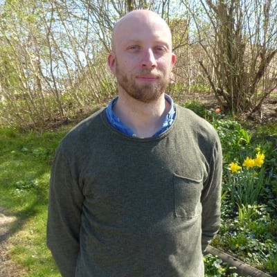 Carl Sebastian Lindberg utomhus. Grön gräsmatta, lite tulpaner, påskliljor och blå himmel i bakgrunden