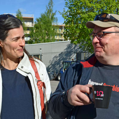 Johanna af Schultén och Paul Holländer poserar på Yles parkeringsplats.