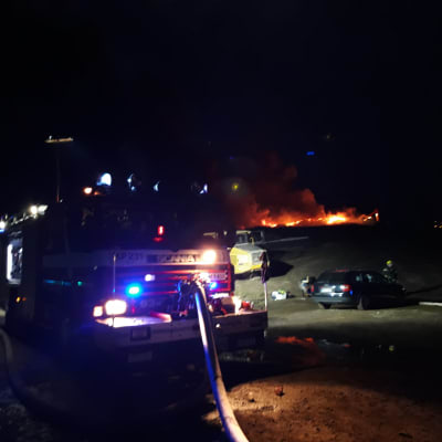 Brandbil framför ett brinnande berg av bildäck vid Jakobstads gamla avstjälpningsplats.