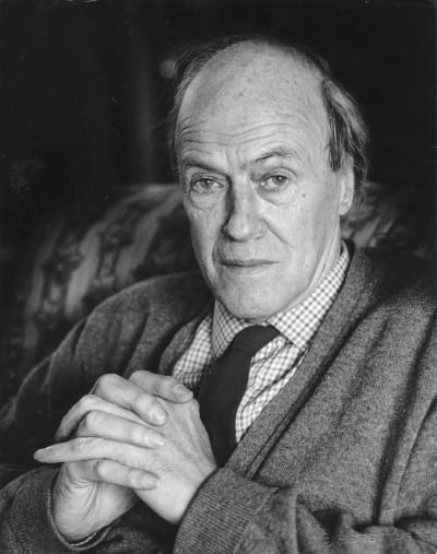 Svartvitt porträtt på den brittiska författaren och poeten Roald Dahl som tittar in i kameran och håller händerna knäppta