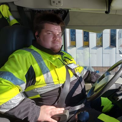 Joni Laaksonen istuu aura-auton ratin takana ja katsoo kameraan