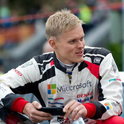 En småleende Ott Tänak utan hjälm iklädd rallyförarkläder.