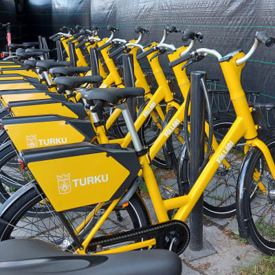 Turun uudet kaupunkipyörät, keltaiset föllärit, odottamassa pyöräilijöitä telineillä. 