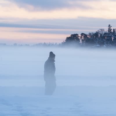 En gammal man går på isen i dimma.