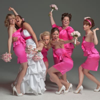 Den kvinnliga ensemblen poserar i rosa klänningar. 