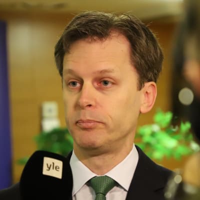 En man i kostym och grön slips intervjuas för TV. 