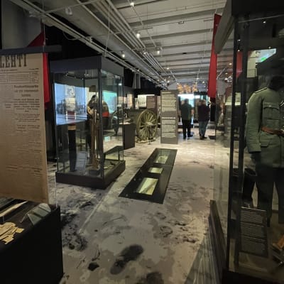 Ihmisiä kulkee museossa sisällissotaa esittelevien vitriinien keskellä.