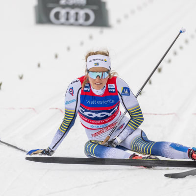 Stina Nilsson sitter på vid spåret utmattad efter målgång.