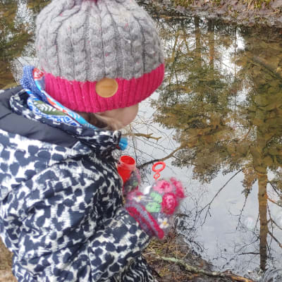 Elvi Sihvonen peilaa pihapiirin lammesta maisemaa.