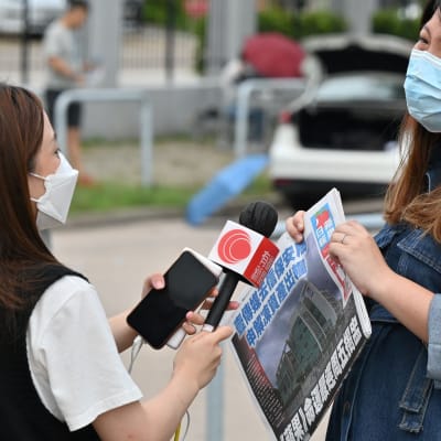En reporter från Apple Daily intervjuar en person som stöder tidningen utanför Apple DAilys högkvarter.