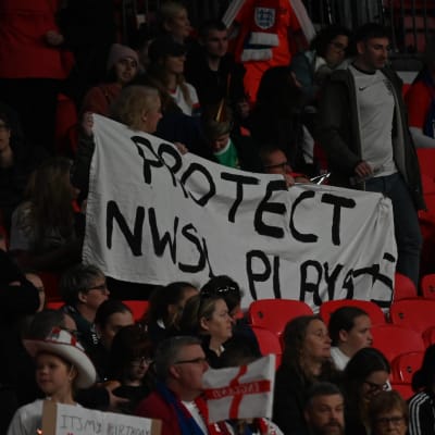 Fotbollsanhängare med en ställningstagande banderoll på läktaren. "Protect NWSL players" - skydda spelarna i NSWL
