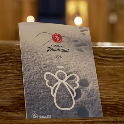 Häfte med julsånger i kyrkbänk.