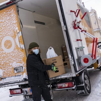 ruokalähetti Renni Sivonen purkaa kuorma-autosta ruokalähetystä.