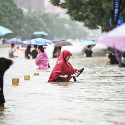Ihmiset kahlaavat kadulla tulvavedessä.