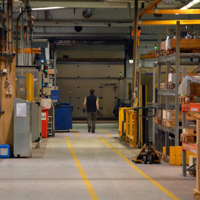 Anställd går längs korridoren i en stor hall i metallföretaget Mapromec.
