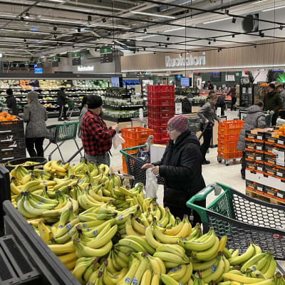 Kuopion Prisman hedelmä- ja vihanneosasto. Nainen ottaa banaaneja pussiin.