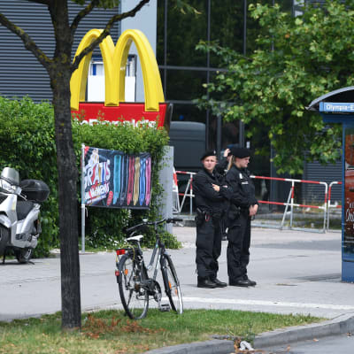 Poliser står utanför köpcentret Olympia och en McDonald's-logo i München den 23 juli 2016.