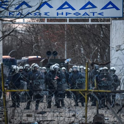 Grekisk kravallpolis stoppar migranterna som samlats vid gränsposteringen Pazarkule på den turkiska sidan. 