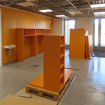 Ett rum för kläder imed orange väggar och skåp. Här ska barn i klasserna 0-2 ha sina ytterkläder och skor.