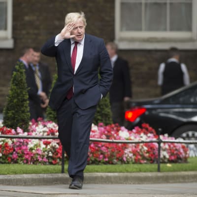 Boris Johnson i svart kostym och röd slips på väg till 10 Downing Street.