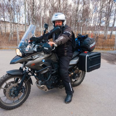 En iklädd motorcykelställ och hjälm sitter på en BMW motorcykel