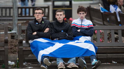 Tre förespråkare för ett självständigt Skottland med en skotsk flagga i famnen