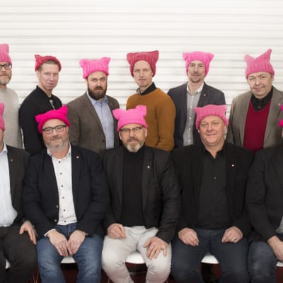 Byggnads styrelse sitter uppradad med ljusröda mössor på huvudet.