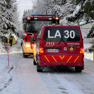 Lapin pelastuslaitoksen pakettiauto ja sammutusauto keulat vastakkain pysäköitynä lumiselle tielle asuinalueella.