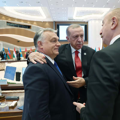 Turkin presidentti kaulailee Unkarin pääministeriä kokoushuoneessa. Takana lippurivi.