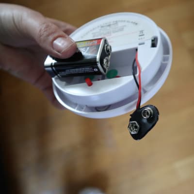 Någon håller i en brandvarnare där batteriet är urplockat.